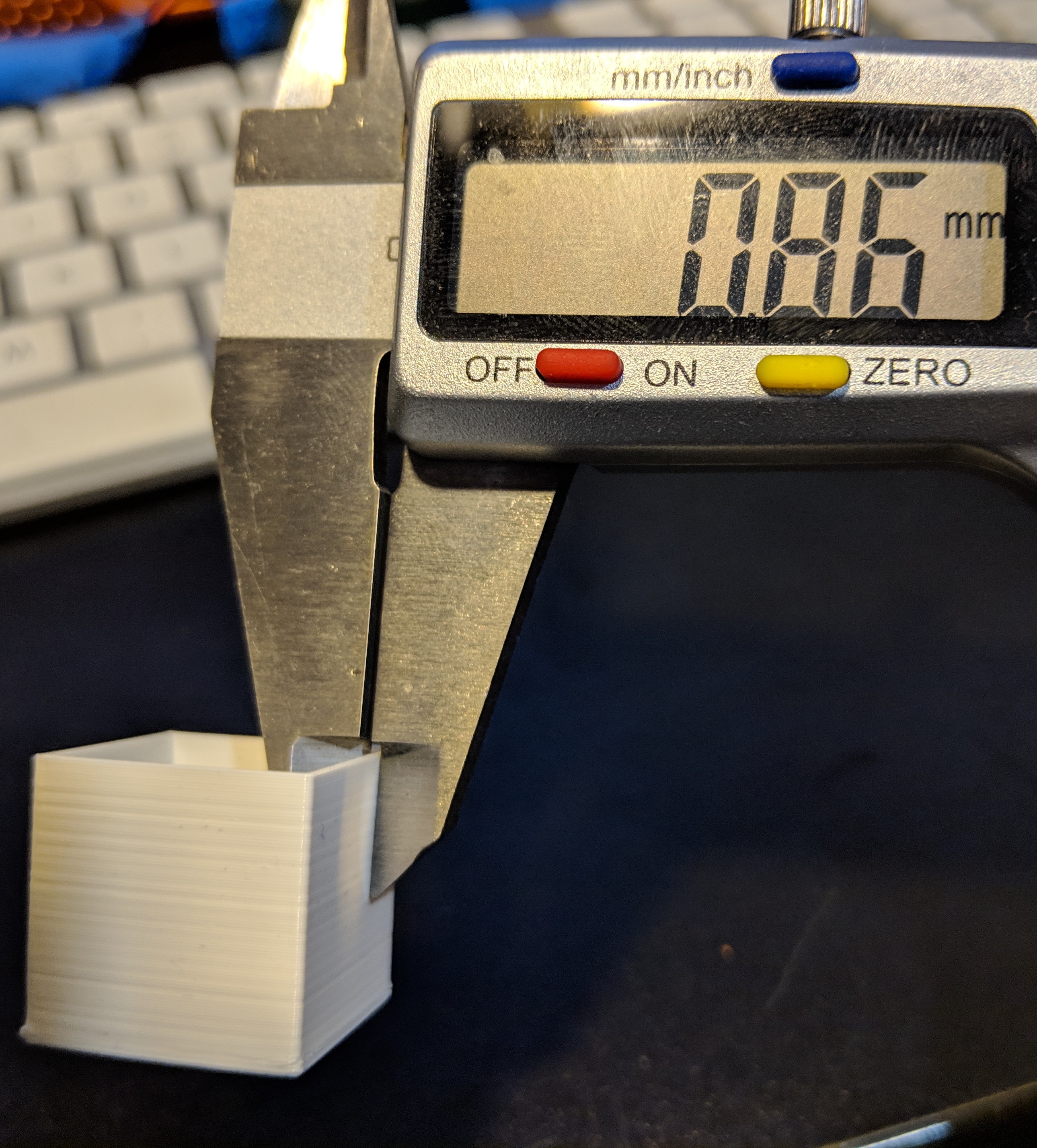 Digital calipers measuring the wall thickness of a single-wall cube.